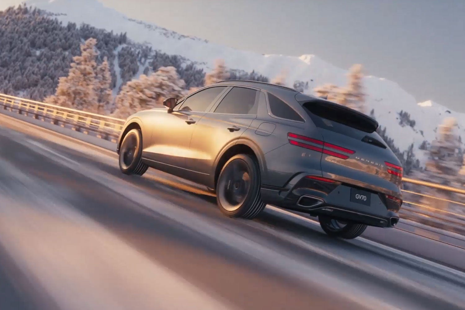 A gray Genesis GV70 SUV drives quickly on a snowy mountain road, sunlight reflecting off its side.